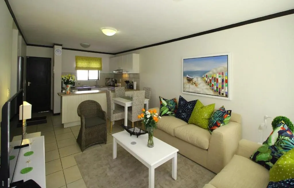 Open-plan kitchen and living area with dining table and colourful scatter cushions