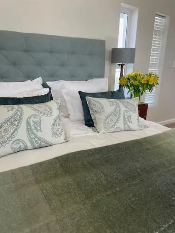 Bed headboard detail with paisley cushions and a vase of yellow flowers