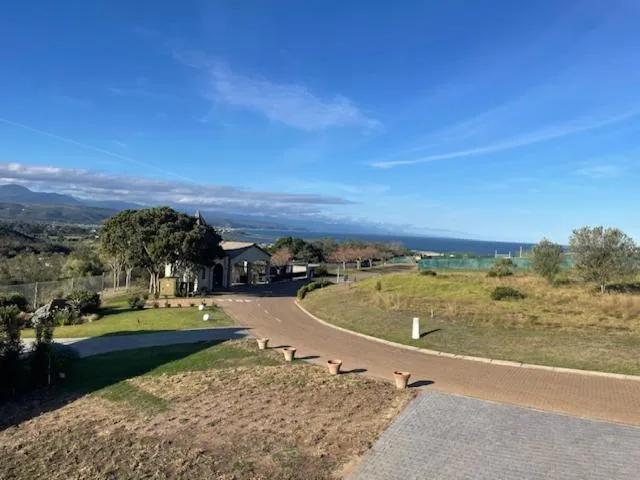 Estate driveway past a gatehouse and lawns with the ocean visible on the horizon