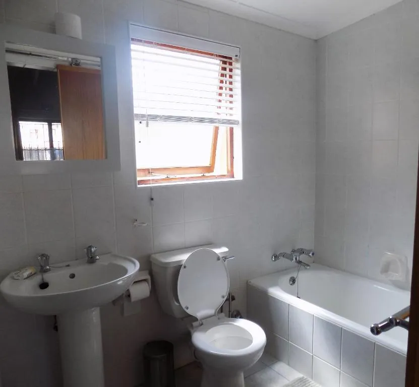 Bathroom with a full bathtub, pedestal basin and a louvred window