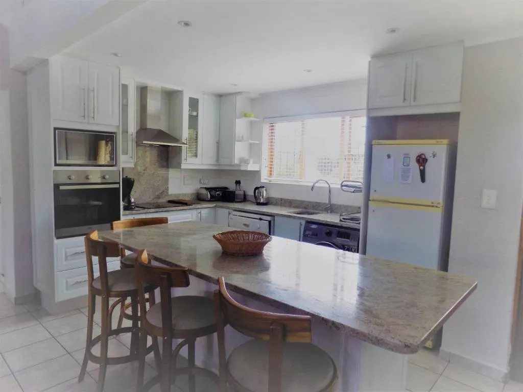 Kitchen with a granite island, built-in oven, bar stools and a full-size fridge-freezer