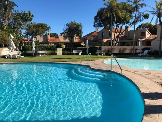 Shared estate swimming pool with palm trees, sun loungers and a second pool beyond