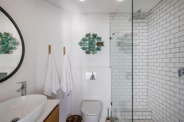 Bathroom with a round mirror, subway-tiled walk-in shower and a freestanding vanity basin