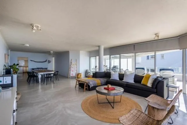 Open-plan living and dining area with a dark corner sofa, round coffee table and dining table for six