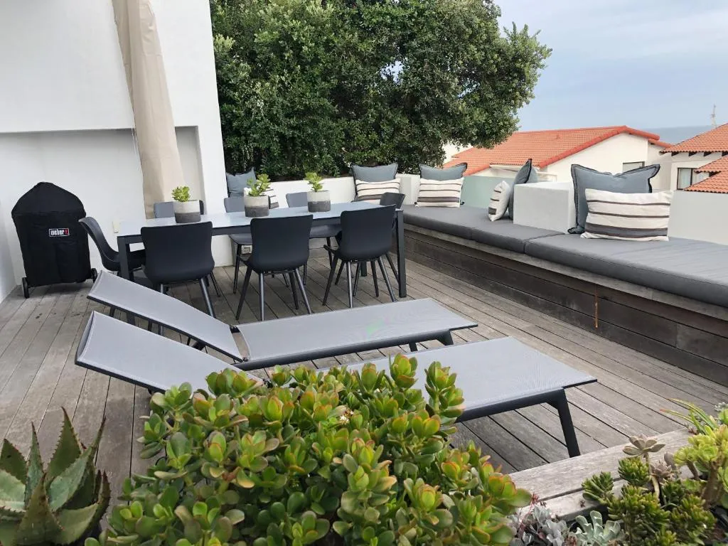 Rooftop deck with a Weber braai, dining table and built-in bench seating overlooking rooftops