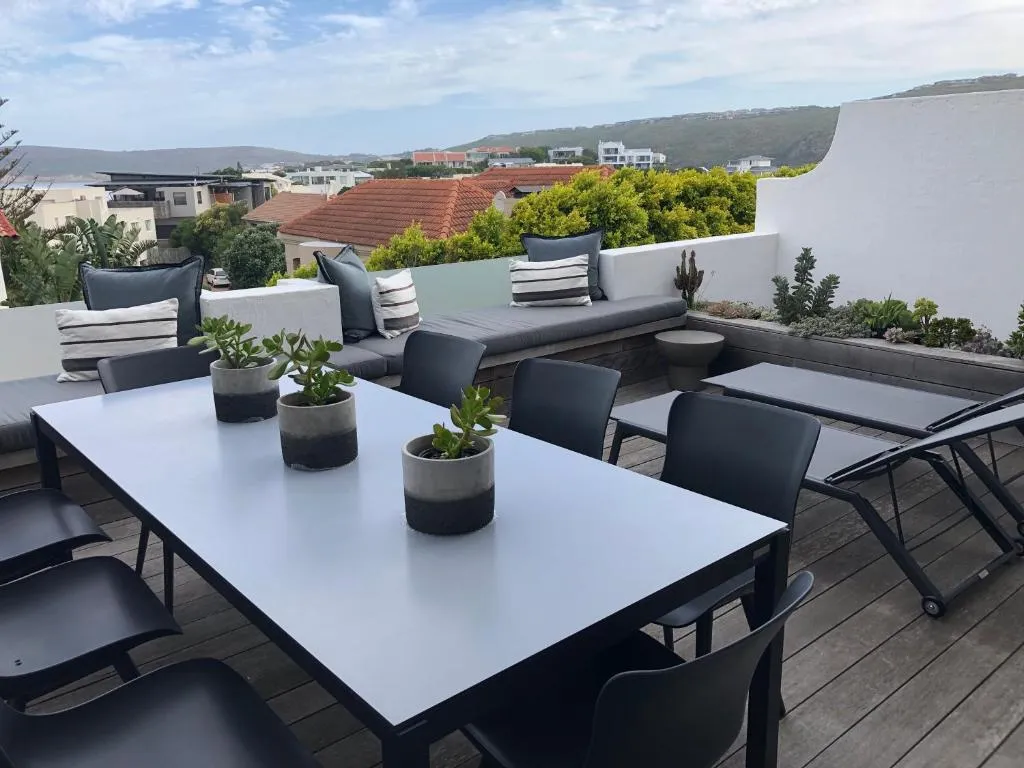 Rooftop dining deck with cushioned bench seating and a view over the hills and neighbouring houses