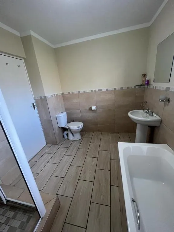 Bathroom with a corner bathtub, pedestal basin and a separate toilet