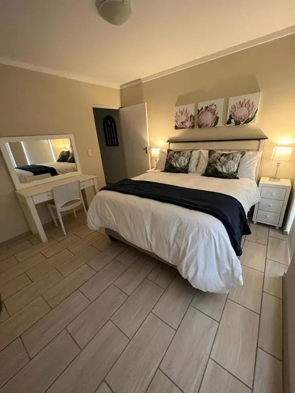 Bedroom with a white bed frame, protea flower prints and a matching dressing table