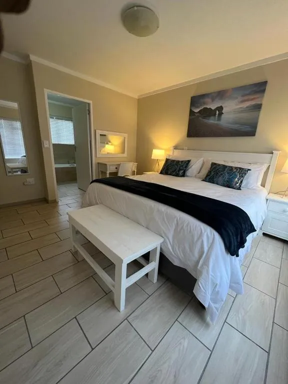 Main bedroom with a coastal-themed canvas above the bed and a door open to the ensuite bathroom