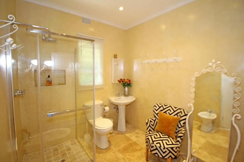 En-suite bathroom with glass-enclosed shower, pedestal basin, bidet and tiled walls