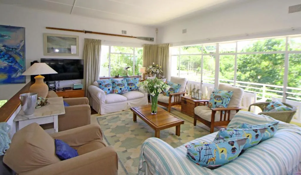 Second lounge area with upholstered armchairs, sofa and doors opening onto a garden deck