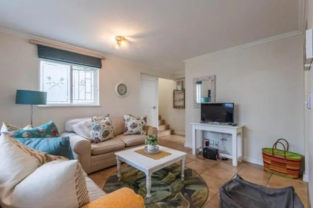 Living room with beige sofas, floral cushions, and a wall-mounted television