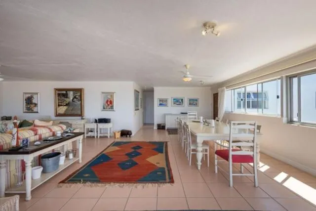 Open living and dining area with a long table seating eight and a patterned rug