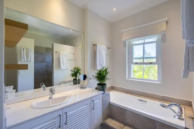Bathroom with a built-in tub, walk-in shower, and garden-facing window