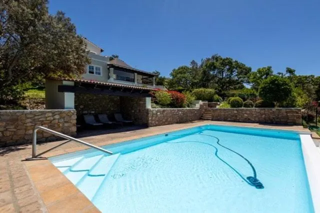Covered stone-walled patio and pool with loungers, set against the house