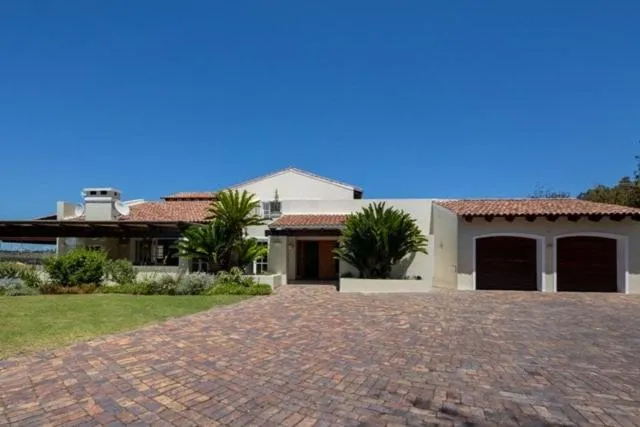 Cape-style villa with double garage, palm trees, and a brick-paved driveway