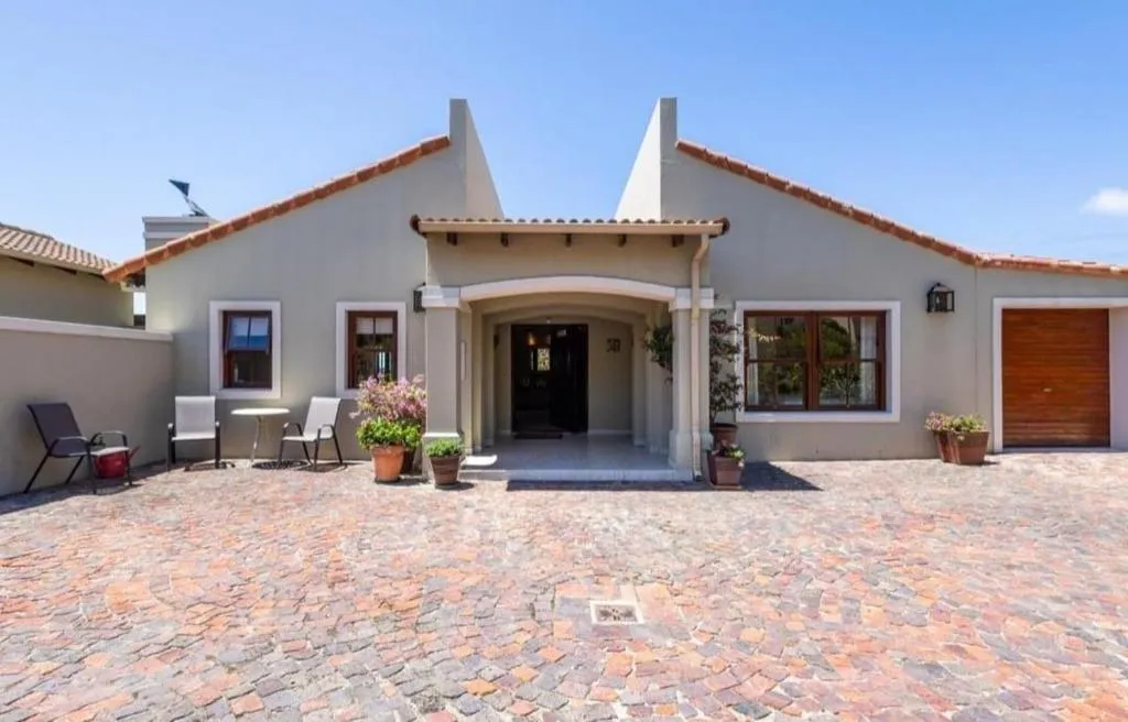 Cape Dutch-style entrance with terracotta roof, archway and cobblestone driveway