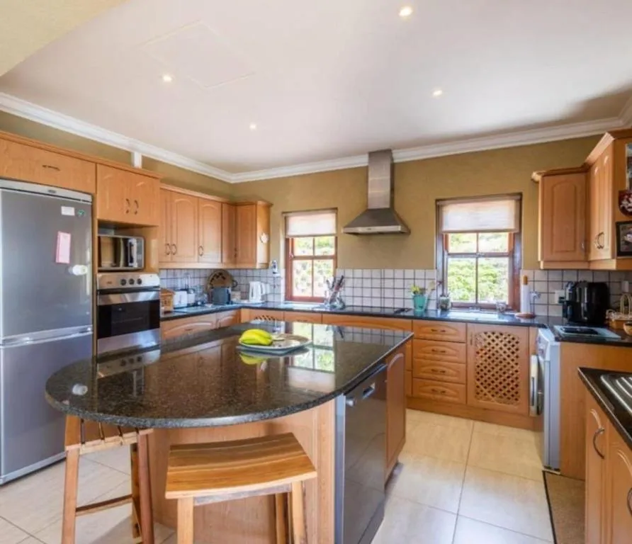 Kitchen island with granite counter, bar stools and light wood cabinetry