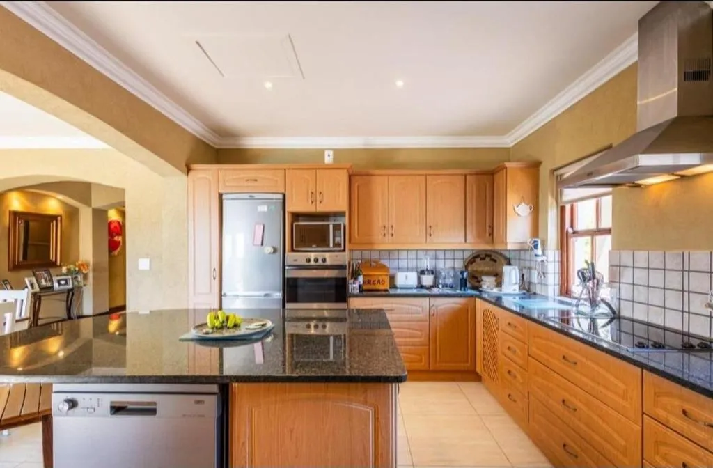 Wide kitchen view with stainless appliances, tiled floor and garden-facing windows
