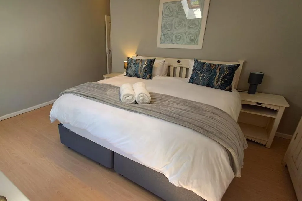 Double bedroom with white bedside tables and a doorway leading to the hallway
