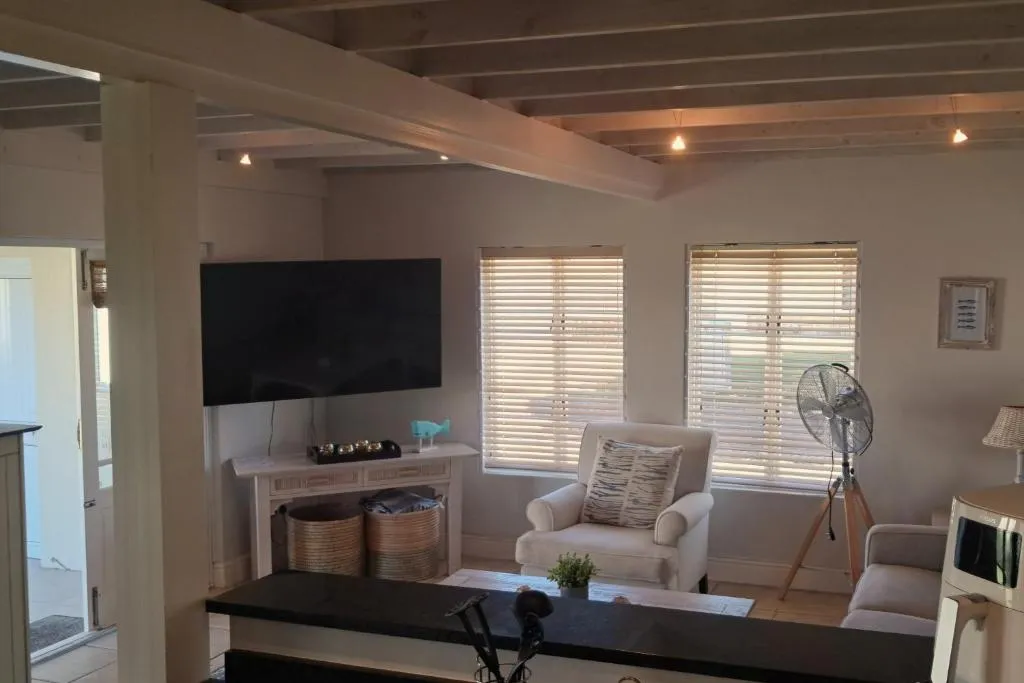 Living room with a wall-mounted TV, beige armchair and exposed beam ceiling