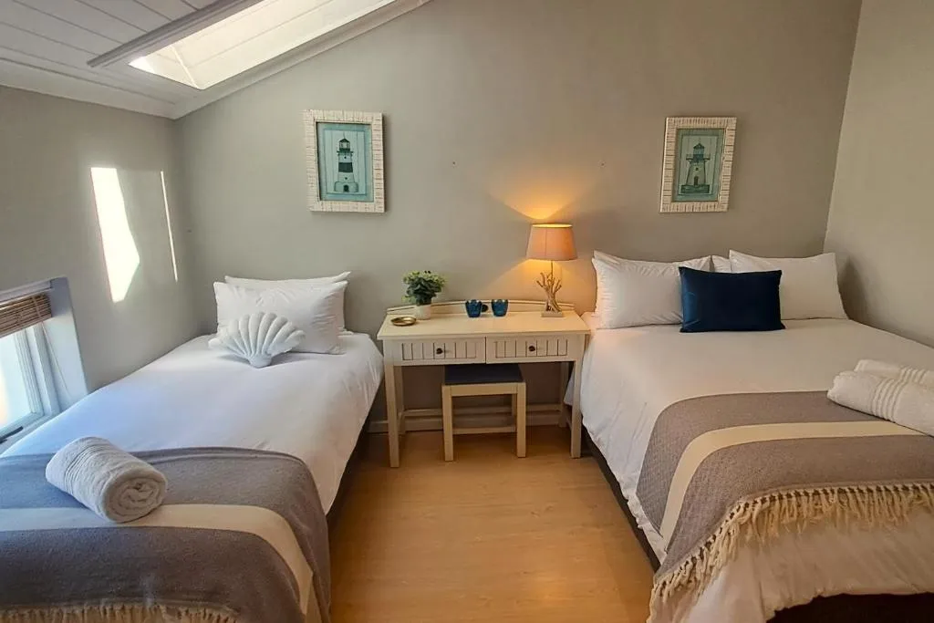 Twin bedroom with lighthouse prints, a shared desk and matching bedside lamp