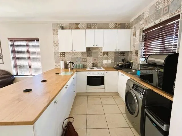 Kitchen with white cabinetry, a tiled splashback, oven and built-in washing machine