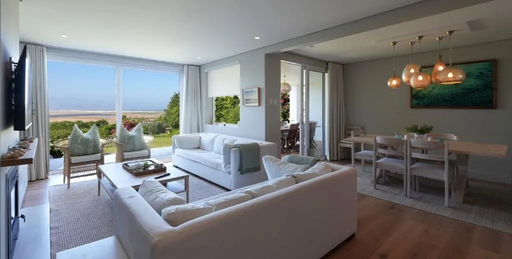 Living and dining area with sofas, a wood dining table and sliding doors onto the lagoon view