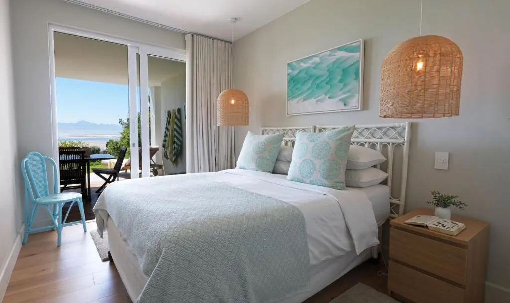Main bedroom with a rattan headboard and a private balcony overlooking the lagoon