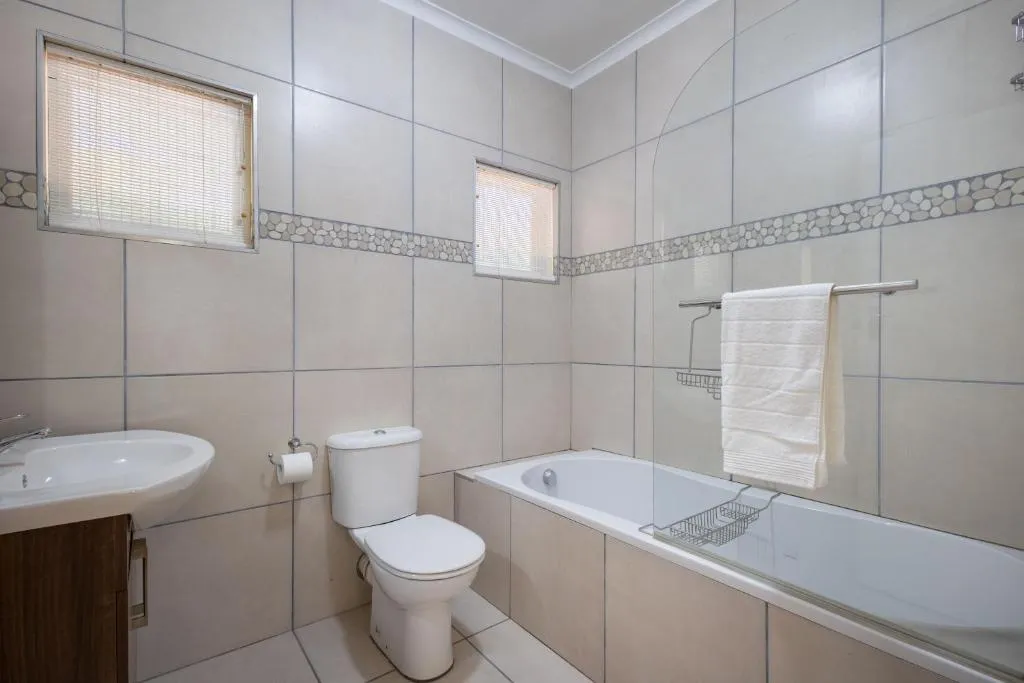 Bathroom with bath, toilet and a pebble tile trim, lit by two frosted windows