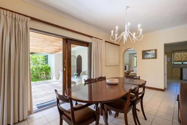 Dining room seating six with sliding doors open to the covered patio and a glimpse of the kitchen beyond