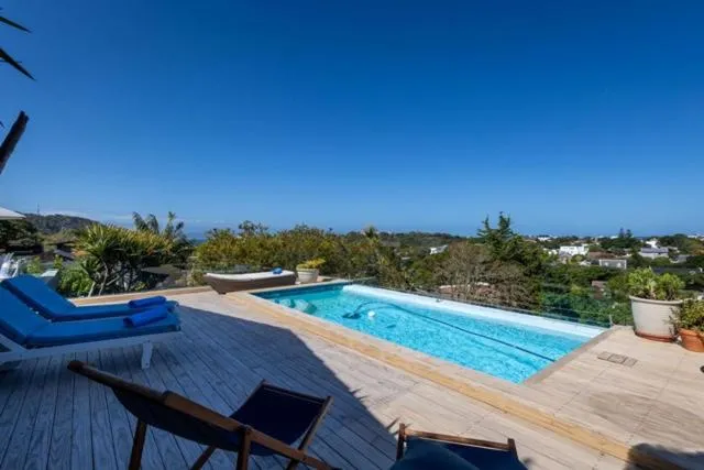 Long lap pool on a wooden deck overlooking wooded hills and the town beyond