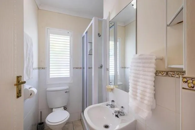 Bathroom with a glass shower cubicle, toilet and pedestal-style vanity