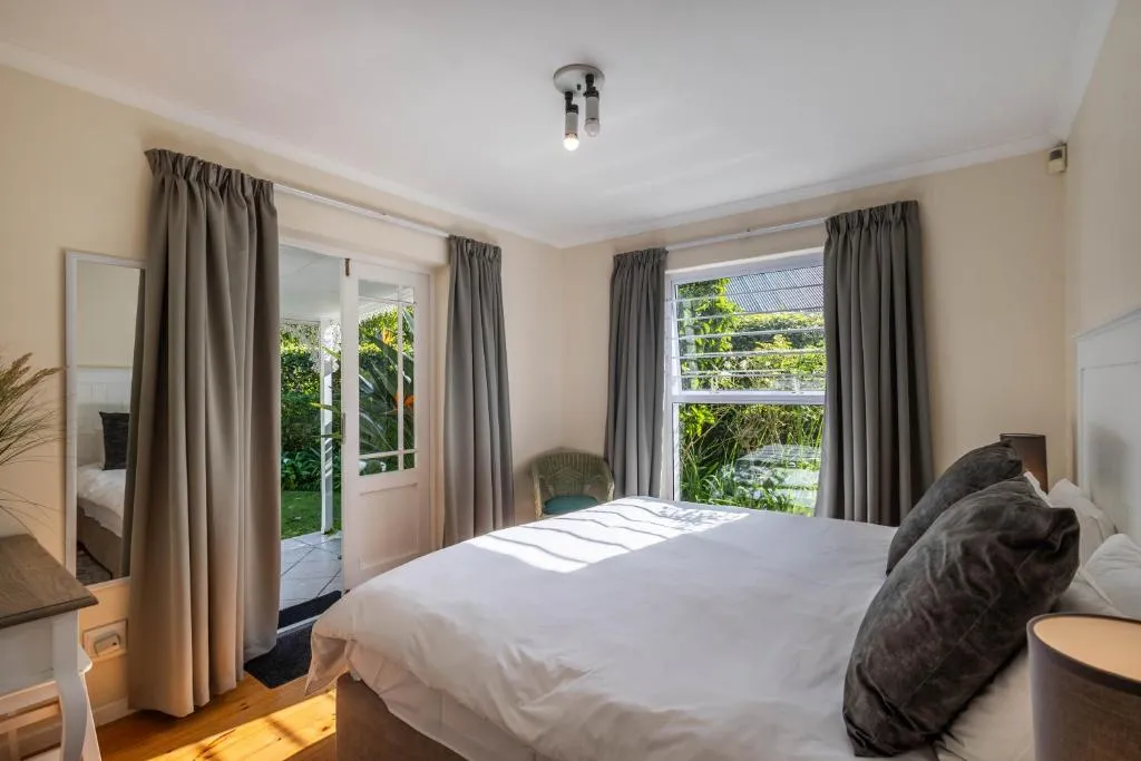 Bedroom with French doors opening directly onto the garden and a wicker chair