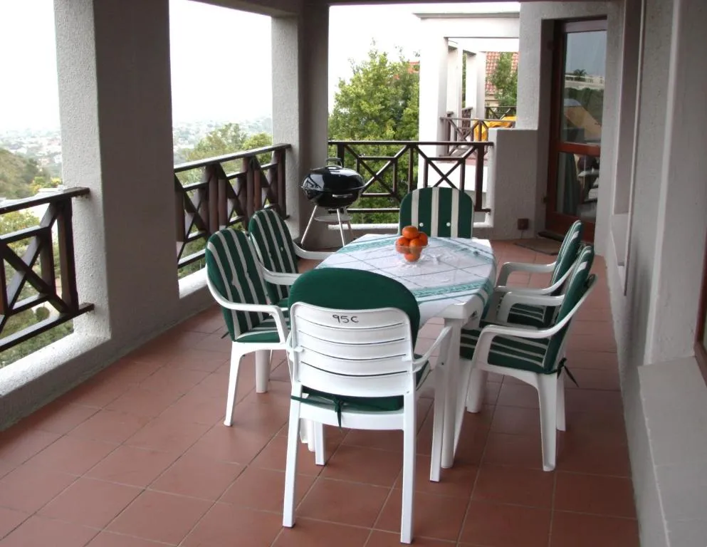 Covered balcony dining table for six with a braai and glimpses of the hillside view