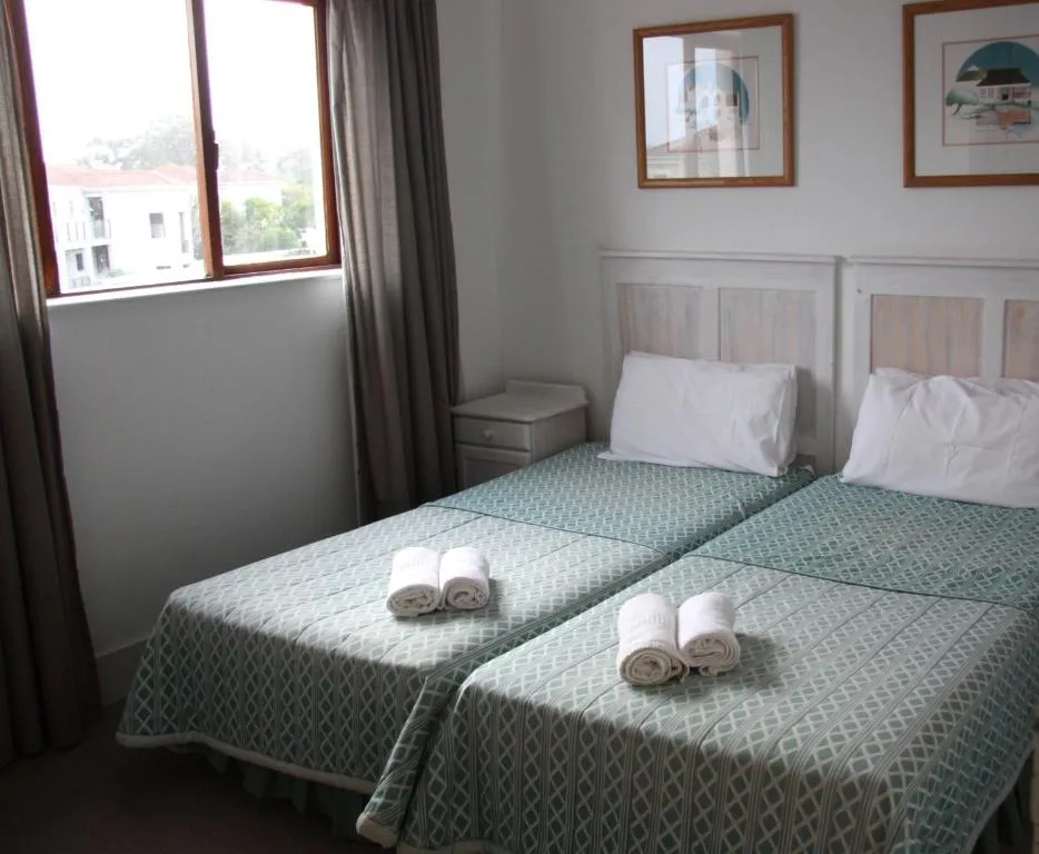 Twin bedroom with two single beds, striped throws, and a window over the street