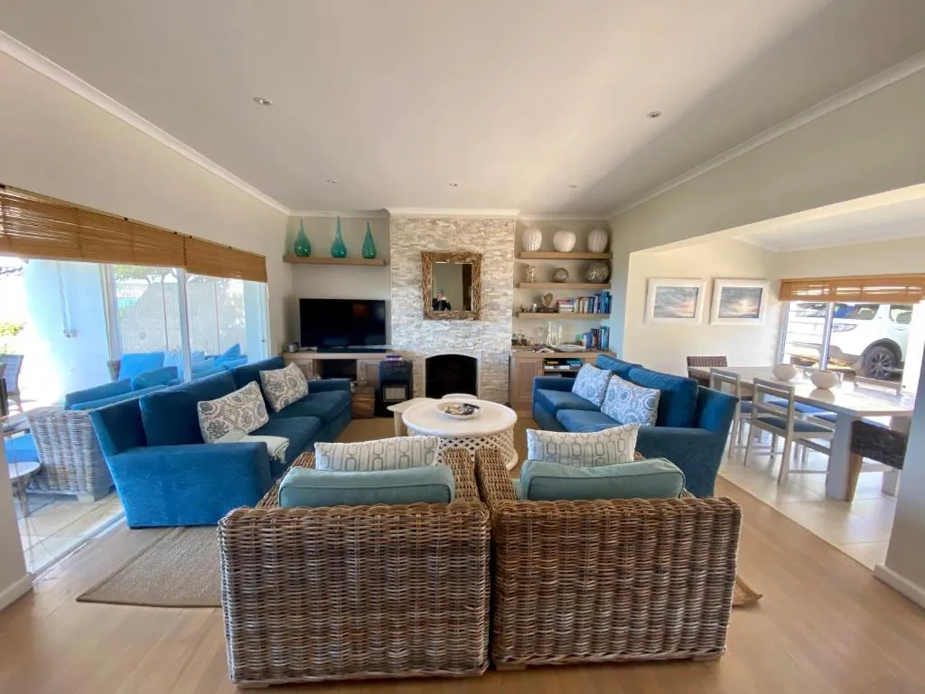 Open-plan living room with blue sofas, wicker armchairs and a stone-clad fireplace