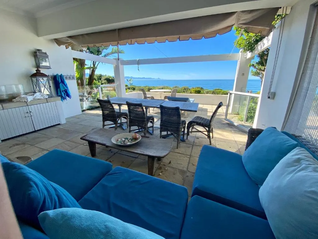 Covered patio lounge and dining area under an awning, opening onto uninterrupted sea views