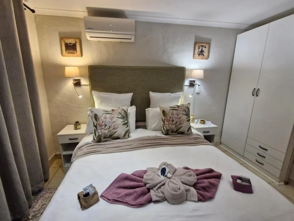 Bedroom with olive headboard, wall-mounted air-conditioner and a decorative towel display