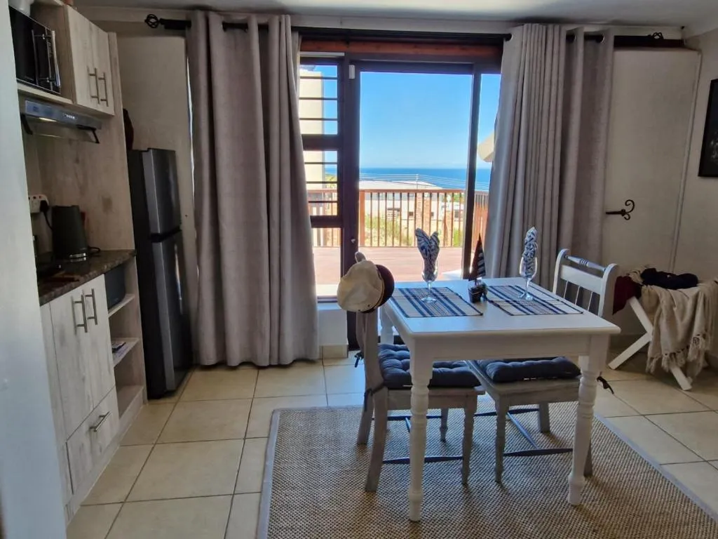 Dining table beside a kitchenette window with a sea view over the balcony railing