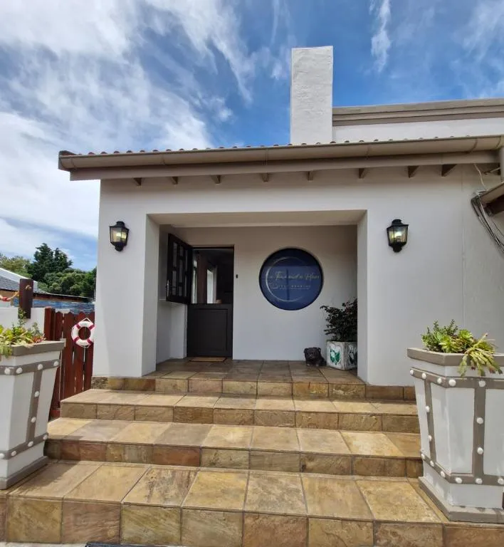 Whitewashed entrance porch with tiled steps and the property's round signage