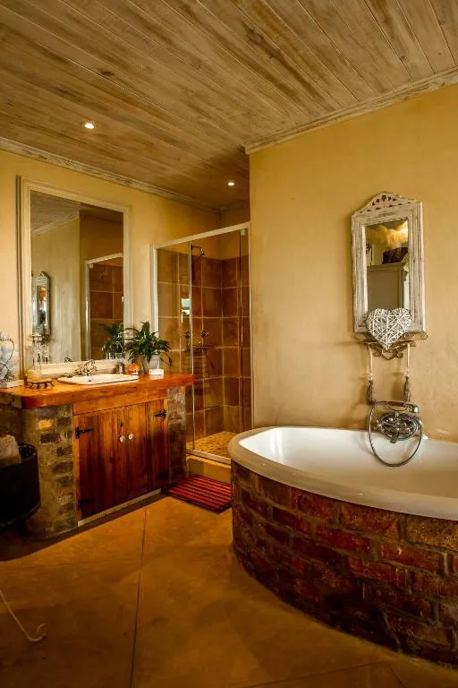 Rustic bathroom with a brick-clad bathtub, timber ceiling, and a separate glass shower