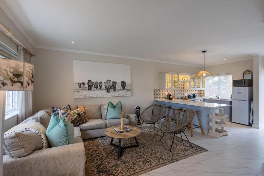 Living and dining area with rattan chairs, a patterned rug and open kitchen beyond
