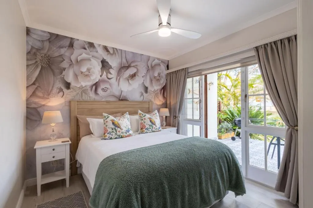 Main bedroom with a floral headboard and glass doors opening onto a paved courtyard