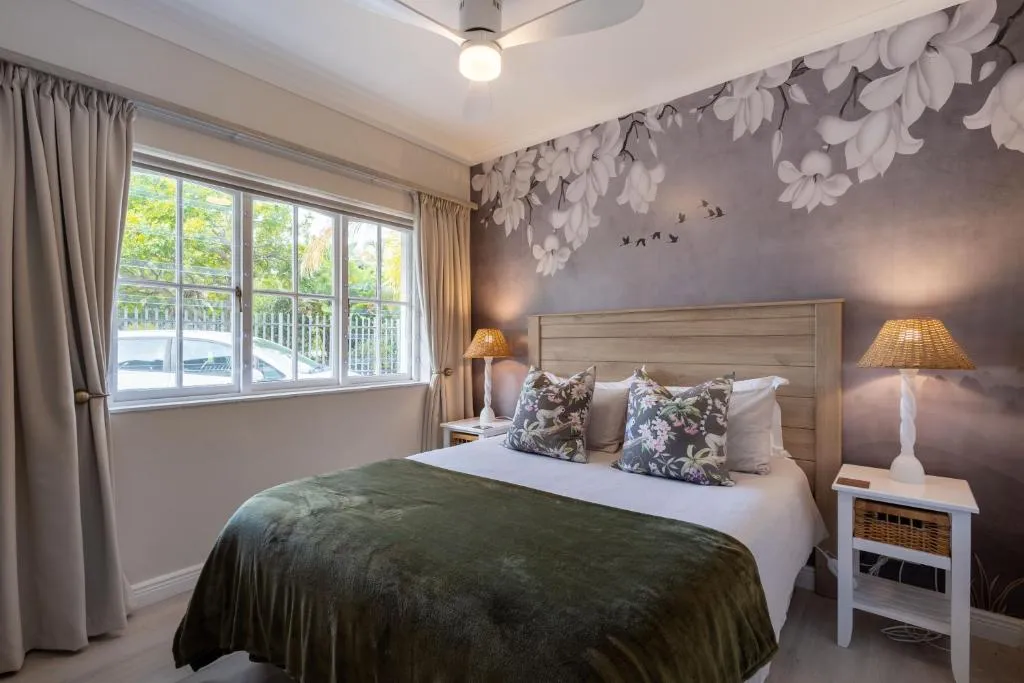 Second bedroom with a floral-mural headboard and a window looking onto the street