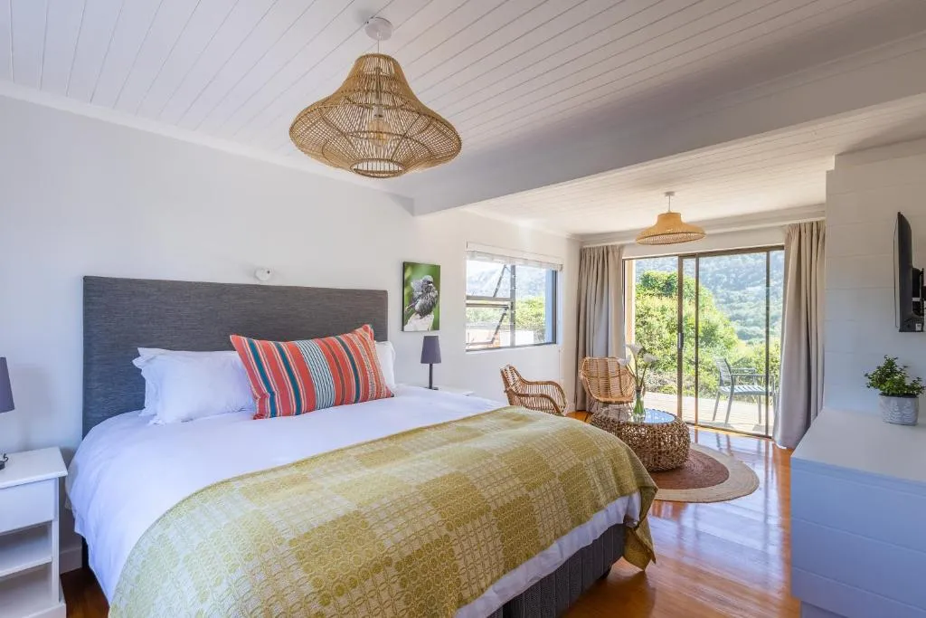 Bedroom with sliding glass doors opening onto a deck overlooking green hillside