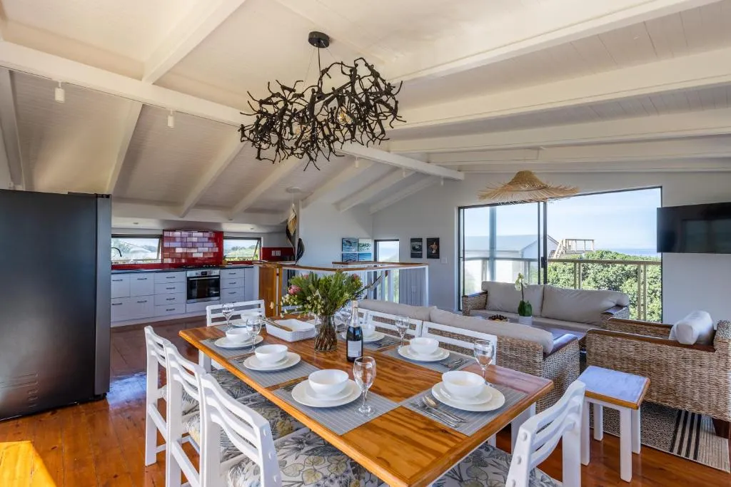 Kitchen and dining area with red-tiled splashback and a glimpse of the sea beyond