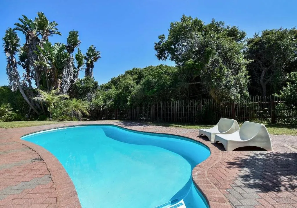 Brick-paved swimming pool terrace bordered by a garden and timber fence