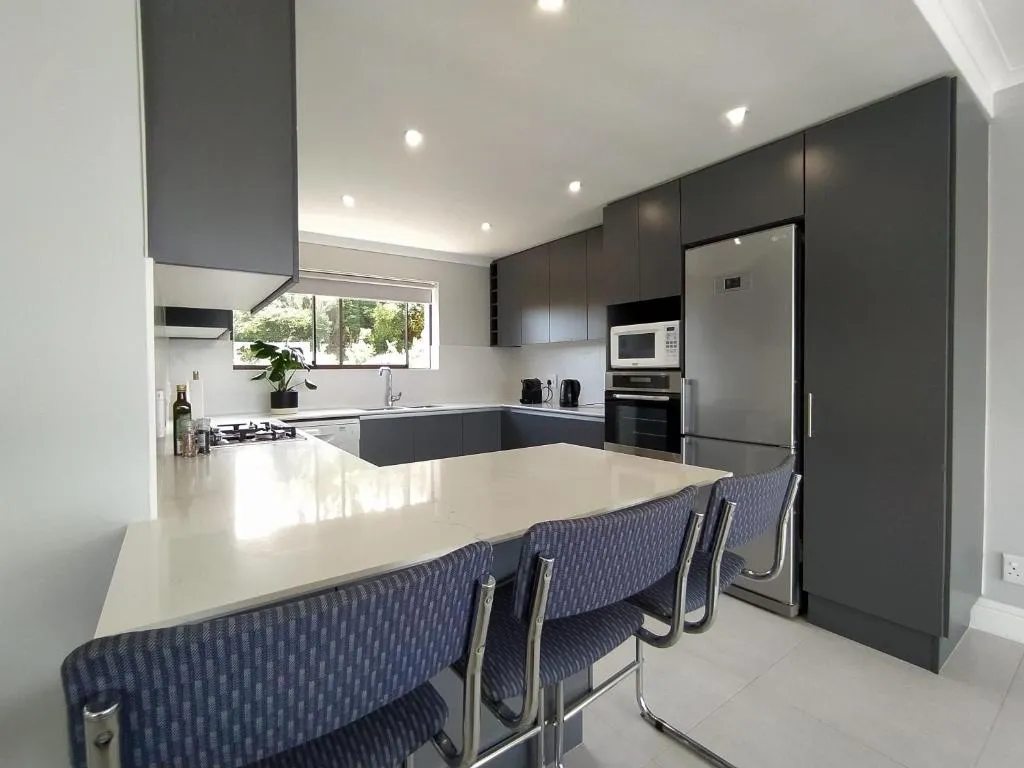 Kitchen with dark grey cabinetry, a marble-look island counter and bar seating