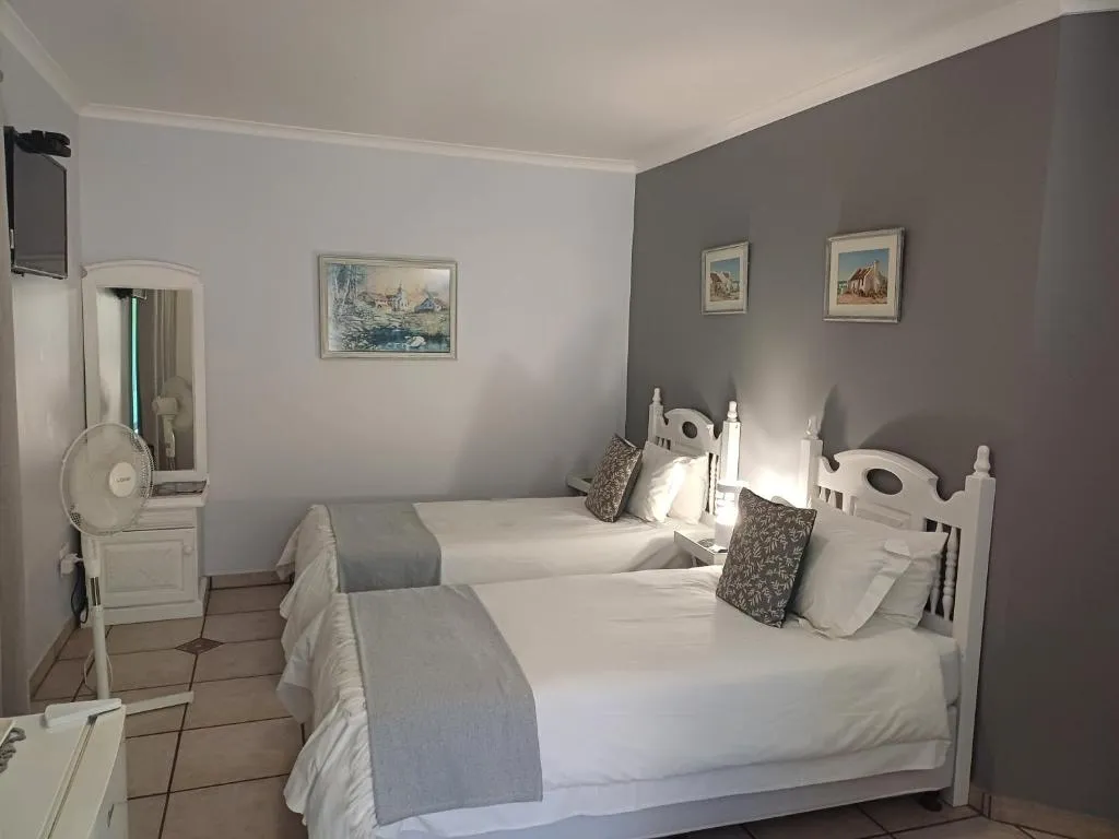Twin room with a charcoal accent wall, floral art prints and a white dressing table
